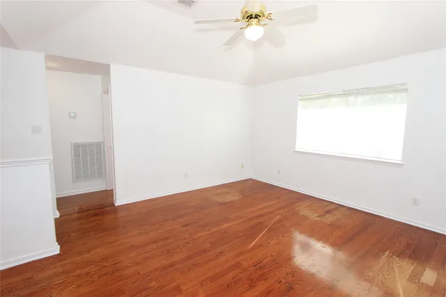 an empty room with wooden floor and windows