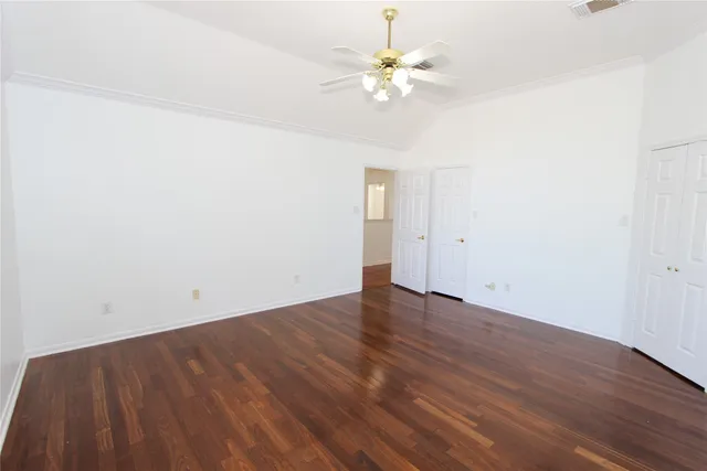 an empty room with wooden floor and chandelier fan