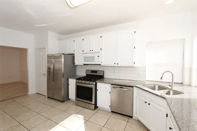 a kitchen with white cabinets and stainless steel appliances