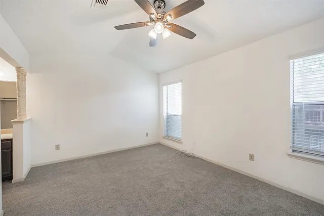 an empty room with windows and fan