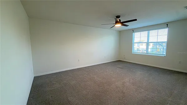 an empty room with a window and a ceiling fan