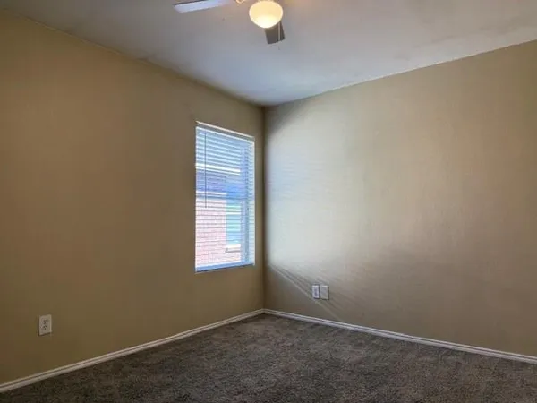 an empty room with a window and a chandelier fan