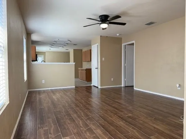 a view of an empty room with wooden floor and a window