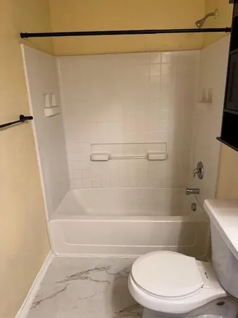 a white toilet sitting next to a bath tub