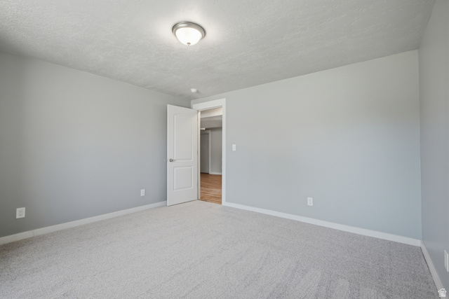 1252 Skyline Road Saratoga Springs, UT 84045 - Photo 37 of 51 Spacious room featuring light gray wall paint, textured ceiling, and light-colored carpet flooring