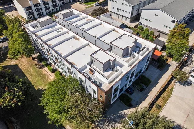 a view of a white house with a fountain and large tree