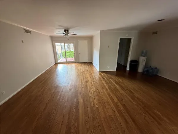 an empty room with wooden floor and ceiling fan