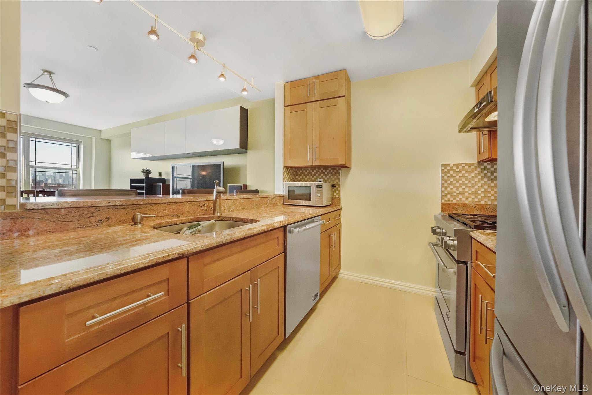 40-40 75th Street, Unit 7C Queens, NY 11373 - Photo 4 of 33 Kitchen featuring stainless steel appliances, light stone countertops, tasteful backsplash, and under cabinet range hood