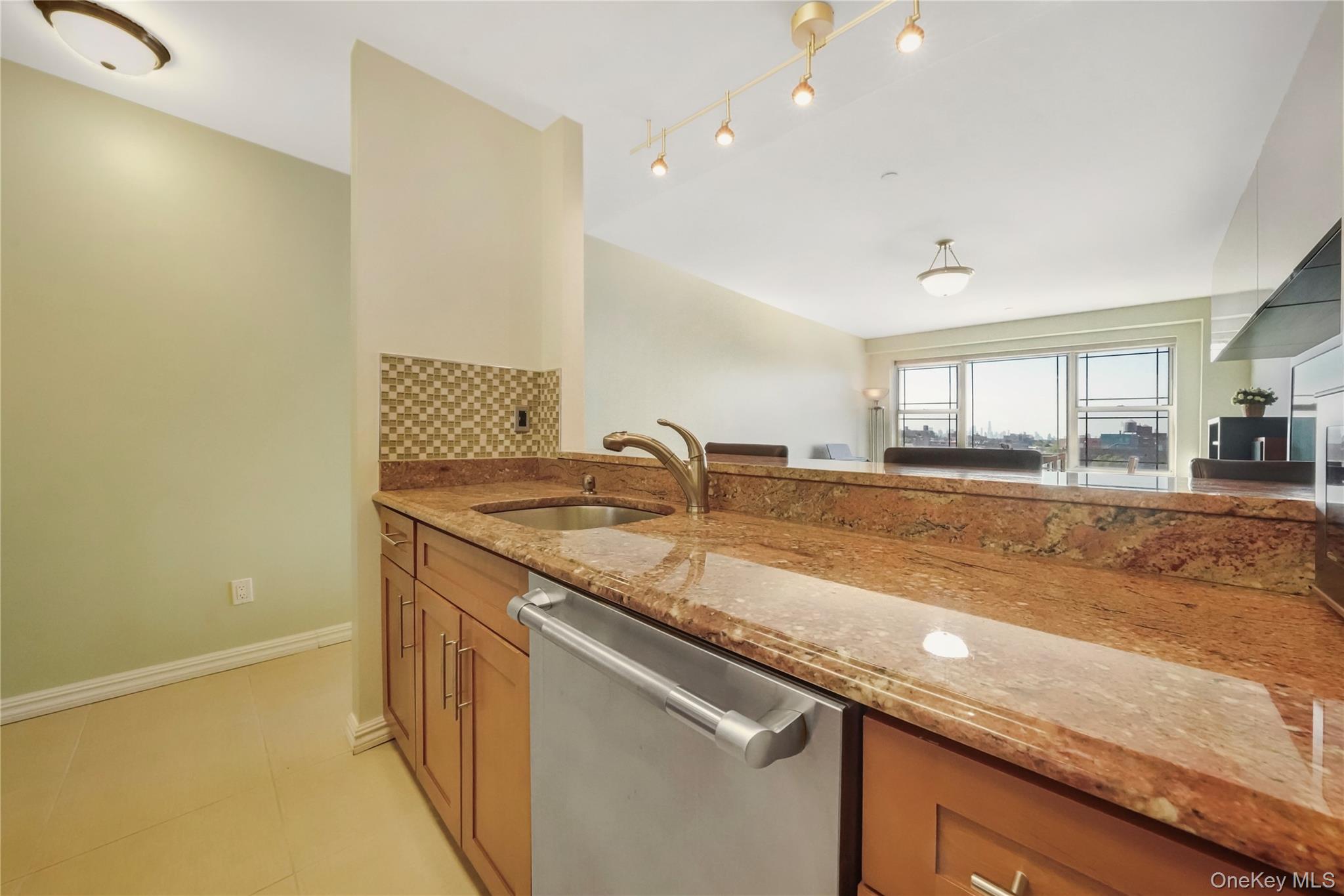 40-40 75th Street, Unit 7C Queens, NY 11373 - Photo 6 of 33 Kitchen featuring brown cabinetry, light stone counters, backsplash, dishwasher, and light tile patterned floors