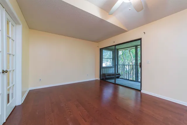 a view of an empty room with a window and wooden floor