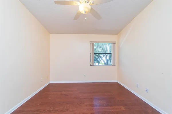 an empty room with a chandelier fan and windows