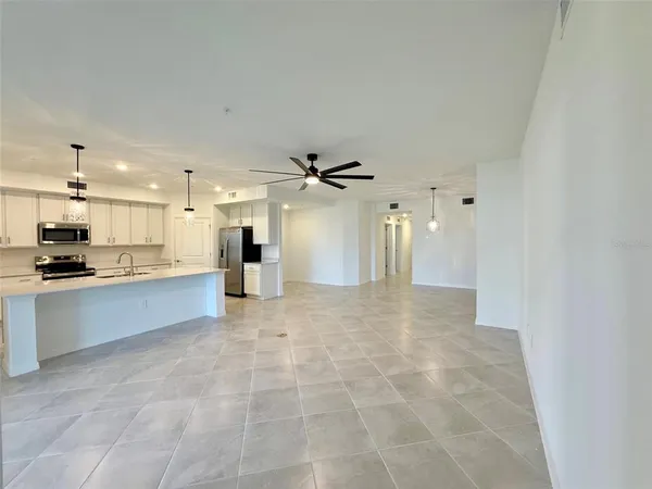 a view of a kitchen with kitchen island white cabinets and stainless steel appliances