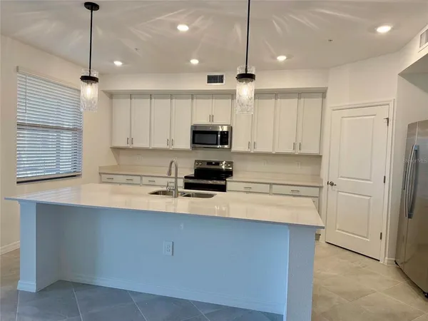 a kitchen with kitchen island a sink stainless steel appliances and white cabinets
