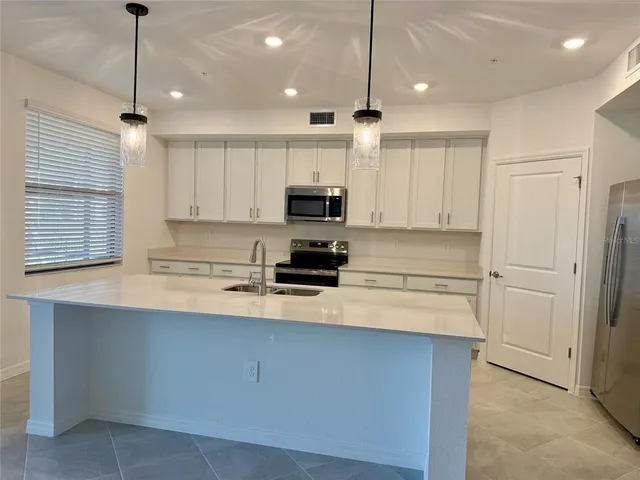 a kitchen with kitchen island a sink stainless steel appliances and white cabinets