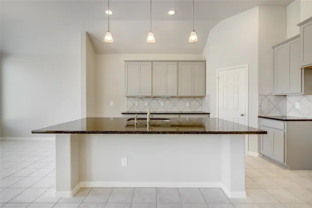 a kitchen with granite countertop a sink and white cabinets
