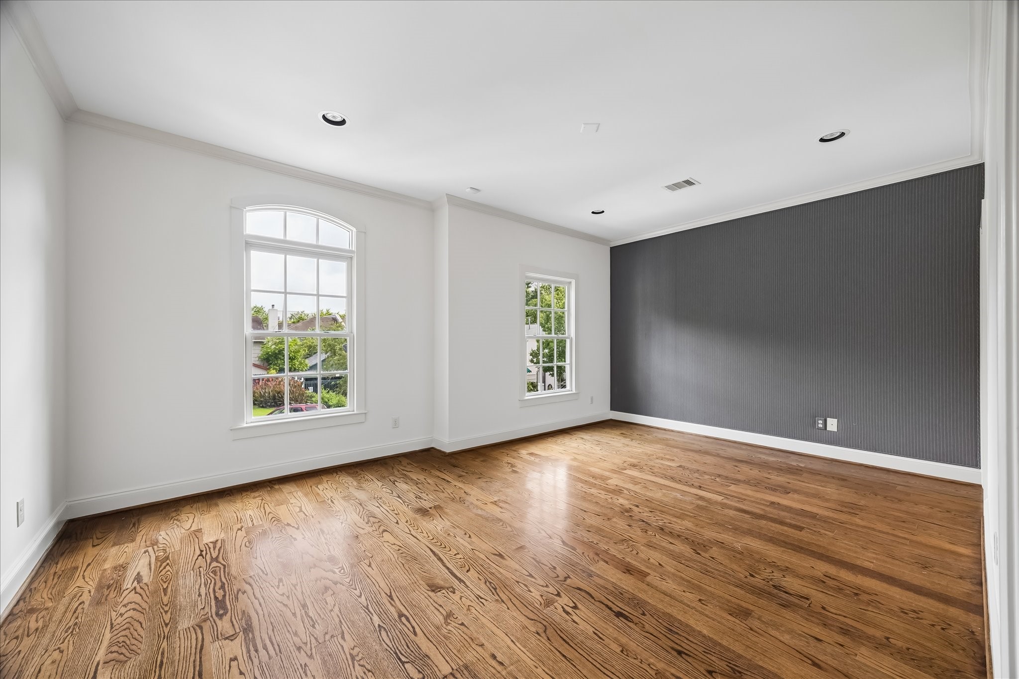 2246 Branard Street Houston, TX 77098 - Photo 34 of 40 Another light-filled secondary bedroom with large windows, a striking accent wall detail, wood floors, and charming neighborhood views.