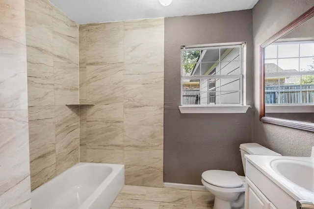 a bath room with a toilet a bath tub and a shower