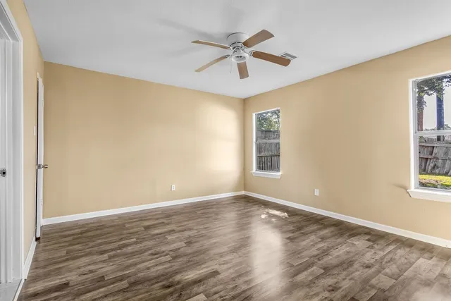 a view of a big room with wooden floor and windows
