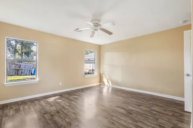a view of an empty room with window and wooden floor
