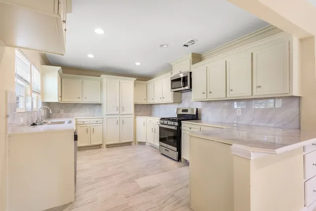 a kitchen with white cabinets and stainless steel appliances