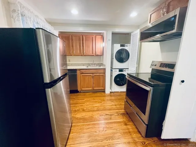 a kitchen with stainless steel appliances granite countertop a refrigerator a stove a sink and dishwasher with wooden floor