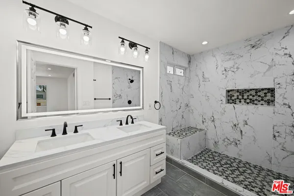 a bathroom with a double vanity sink mirror and shower