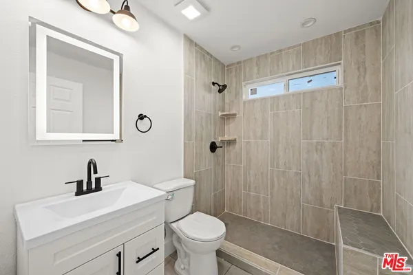 a bathroom with a sink a toilet a shower and a mirror