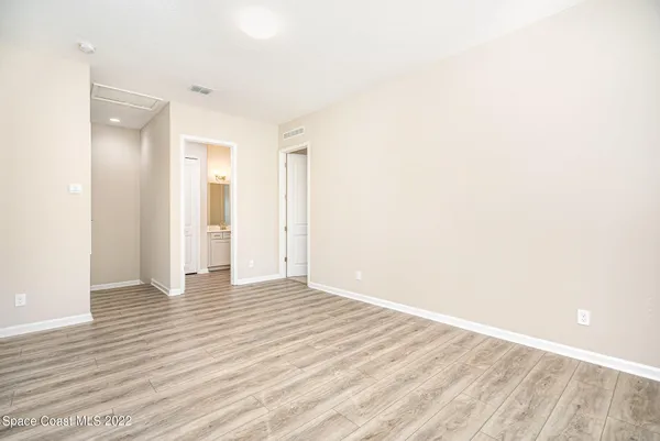 a view of an empty room with wooden floor and a bathroom