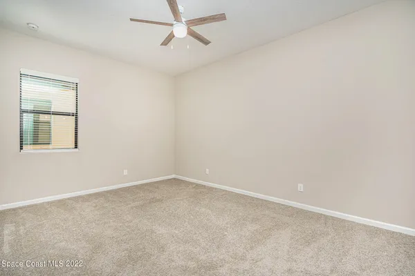 an empty room with a window and a fan