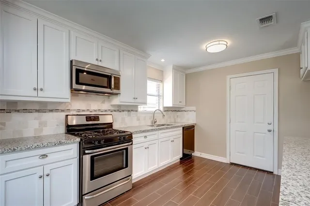 a kitchen with granite countertop a sink cabinets and stainless steel appliances