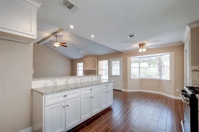 a hall with kitchen island white cabinets and wooden floor