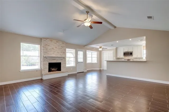 an empty room with wooden floor fireplace and windows