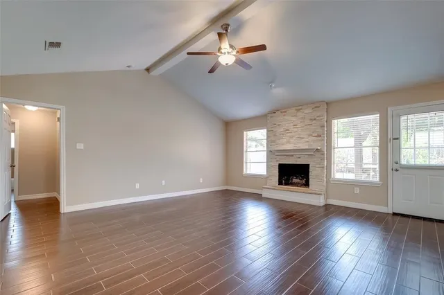a view of an empty room with wooden floor fireplace and a window
