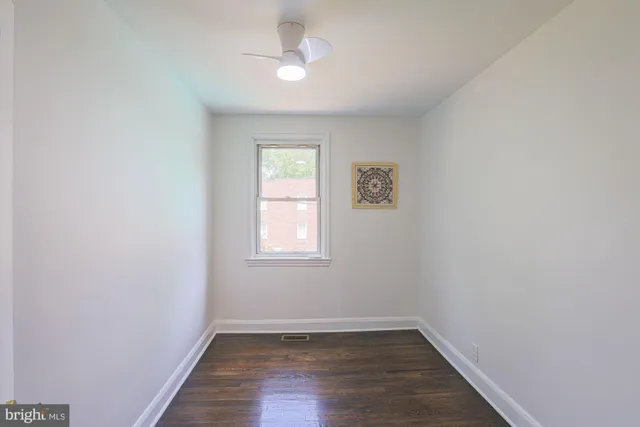 an empty room with a window and hardwood floor