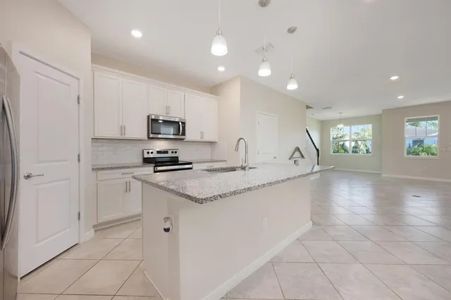 a kitchen with granite countertop a stove top oven a sink a counter space and cabinets