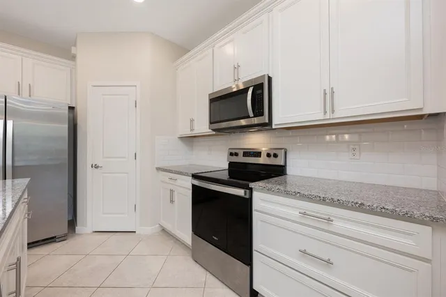 a kitchen with stainless steel appliances granite countertop white cabinets and a stove a refrigerator with white cabinets