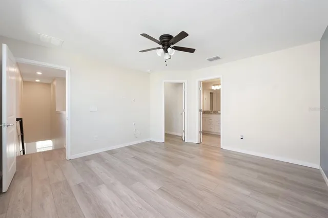 an empty room with a ceiling fan and wooden floor