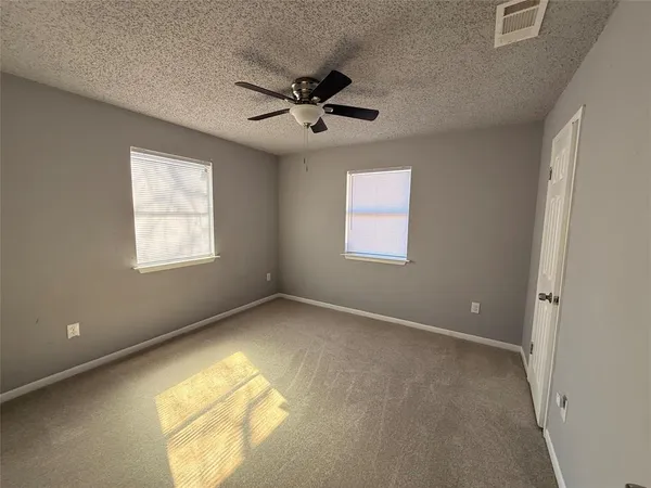 an empty room with windows and fan