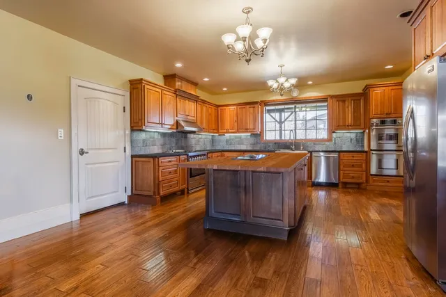 a kitchen with stainless steel appliances kitchen island granite countertop wooden floors and view living room