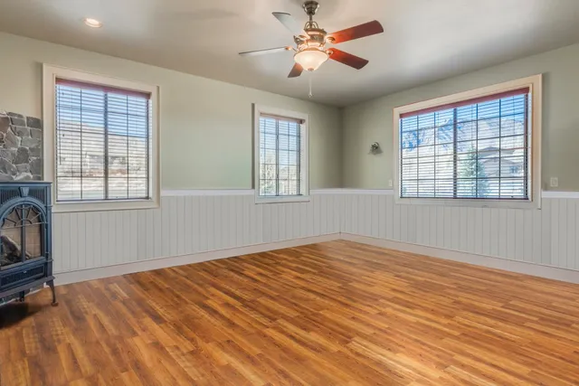 a view of an empty room with a window and wooden floor