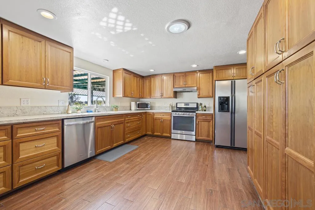 1007 Pepper Tree Lane Fallbrook, CA 92028 - Photo 11 of 34 a kitchen with wooden floors stainless steel appliances and cabinets