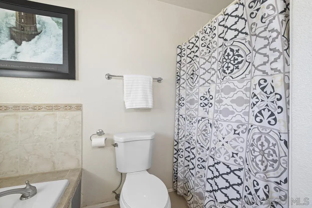 1007 Pepper Tree Lane Fallbrook, CA 92028 - Photo 23 of 34 a white toilet sitting next to a shower curtain