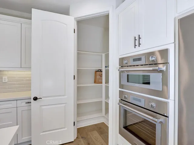 a kitchen with stainless steel appliances a sink dishwasher a refrigerator and white cabinets with wooden floor