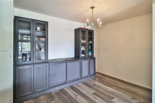 a view of an empty room with chandelier and wooden floor