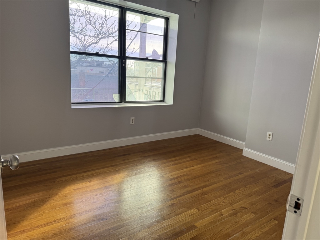 25-31 Maverick Square, Unit 5 Boston, MA 02128 - Photo 16 of 26 an empty room with wooden floor and windows