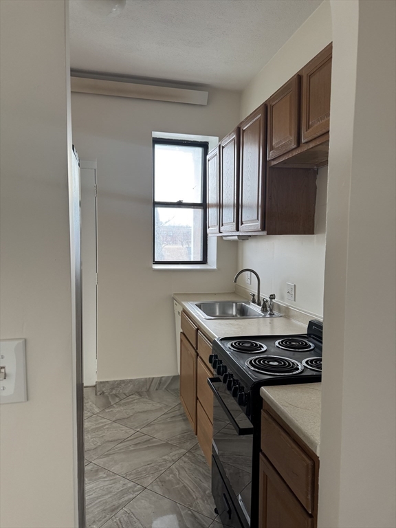 25-31 Maverick Square, Unit 5 Boston, MA 02128 - Photo 21 of 26 a kitchen with granite countertop a stove sink and cabinets