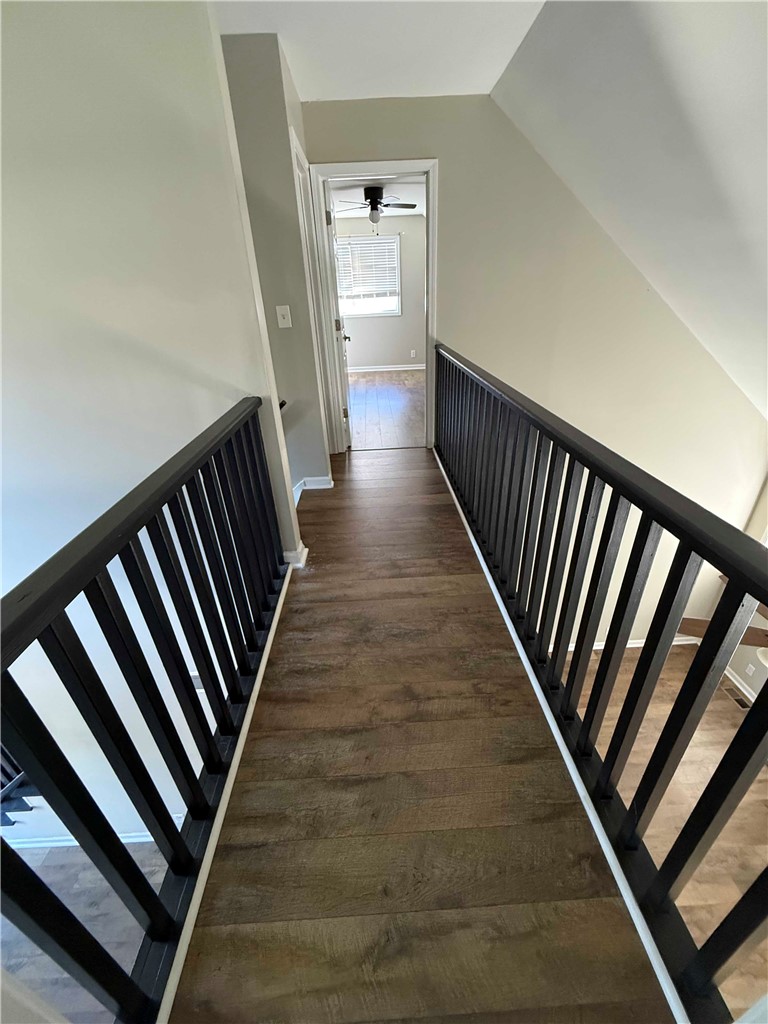 116 Kelly Lane Easley, SC 29642 - Photo 31 of 39 Rich wood-look flooring and dark railings define this upper-level hallway under a sloped ceiling.