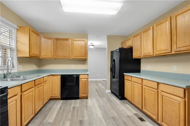 a kitchen with wooden floors stainless steel appliances a sink and cabinets
