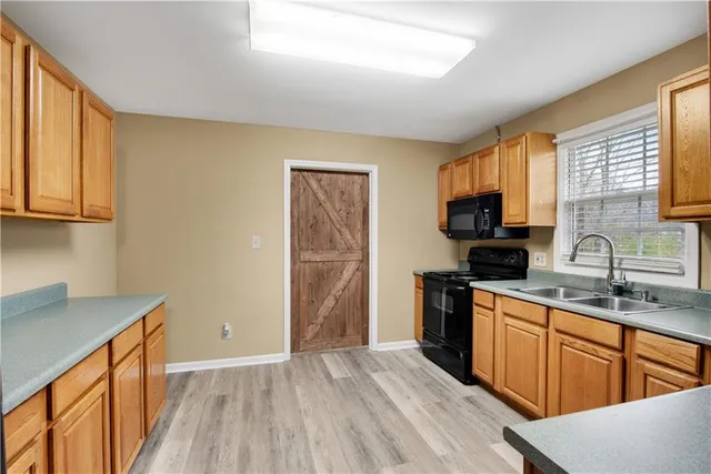 a kitchen with a sink wooden floor and stainless steel appliances