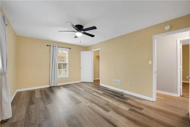 a view of empty room with wooden floor and fan